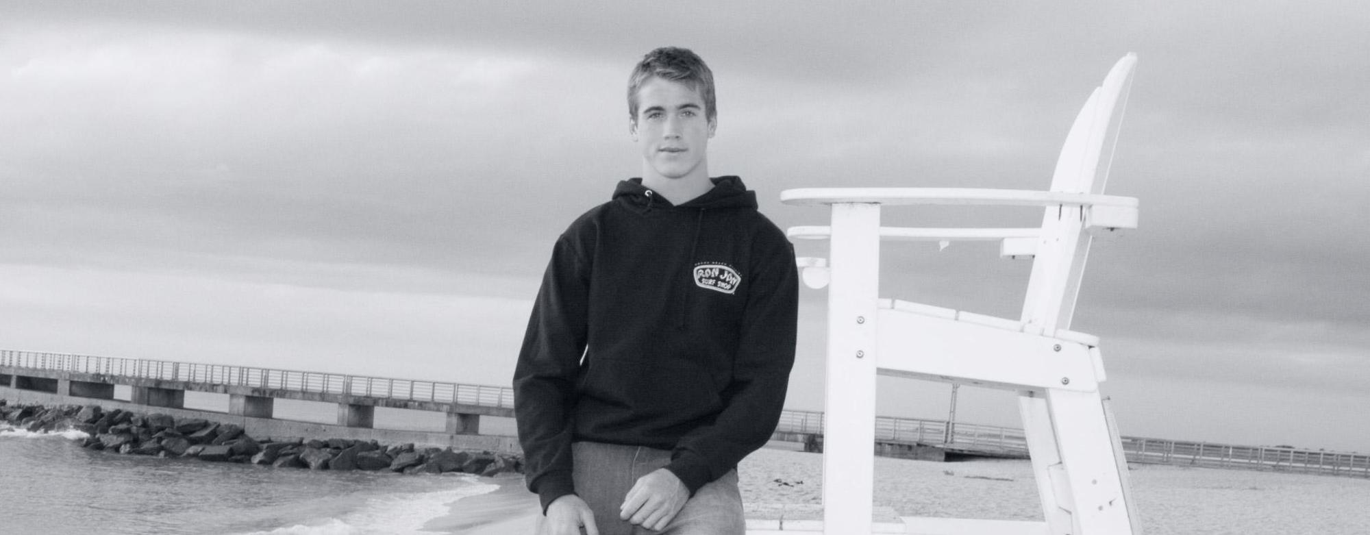 black and white image of a guy in a ron jon hoodie at the pier
