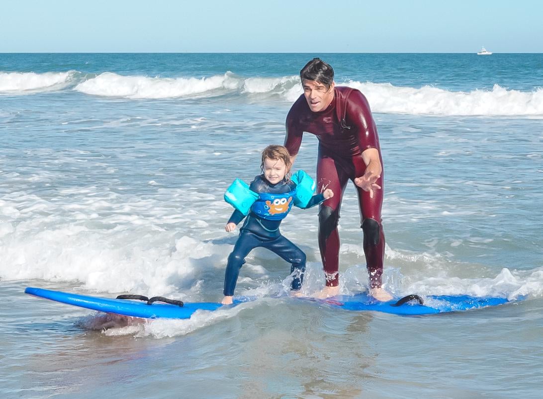 Photo of team rider Randy Townsend helping his daughter surf on a wave