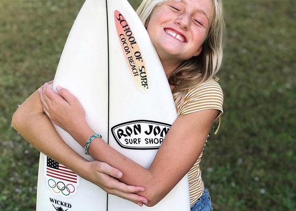 Photo of team rider Kylie Pulcini hugging a surfboard