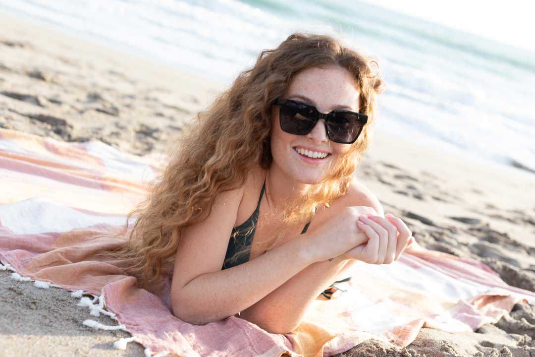 girl on towel at the beach wearing sunglasses