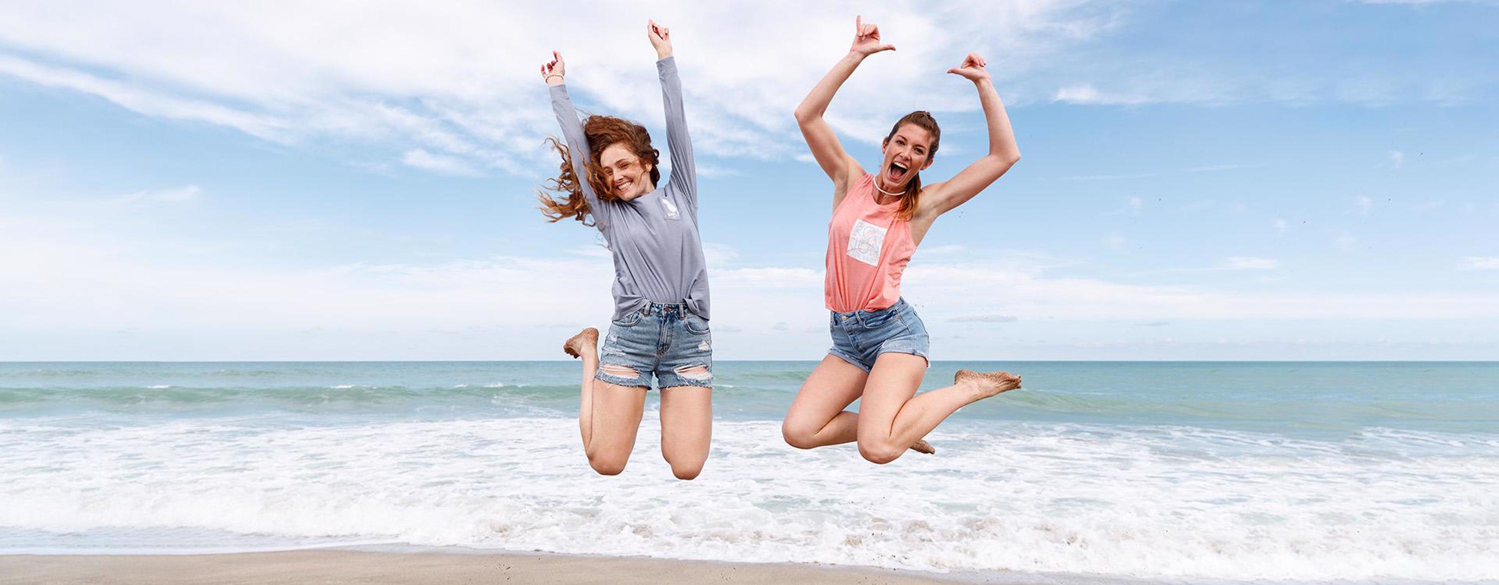 two girls jumping at the beach