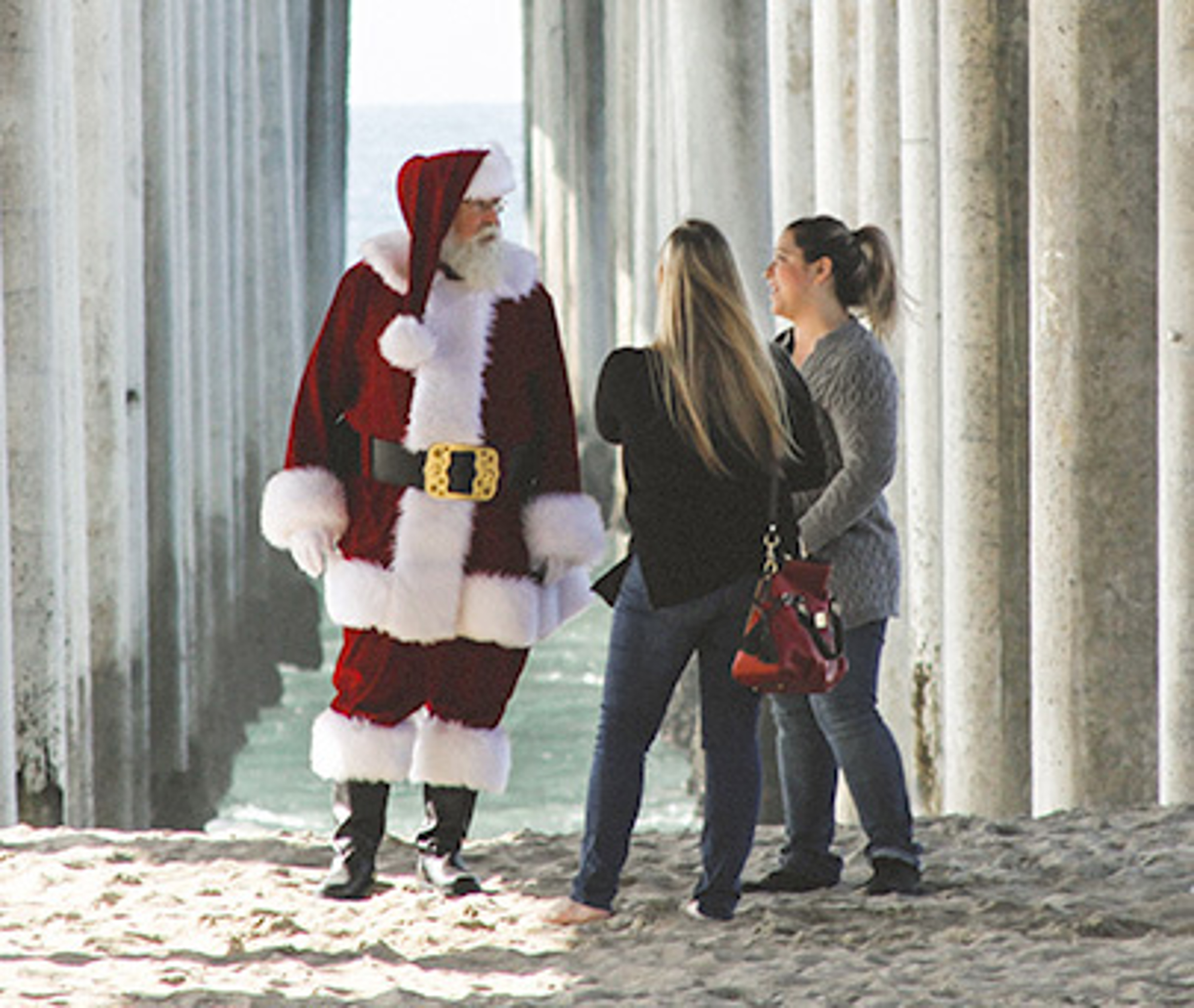 two girls talking with Santa under the pier at the beach