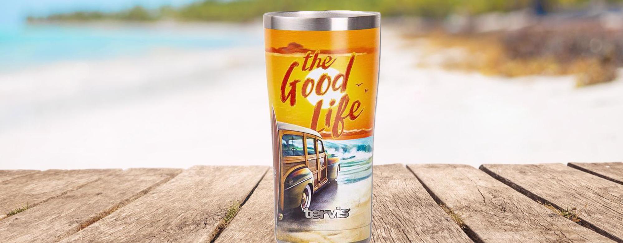 stainless steel good life tumbler on a boardwalk with beach background