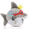 Plush shark toy with gray body, yellow tuft of hair, red goggles, and the words Surf Cruiser on its side.