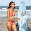 A woman in a red bikini stands on a beach holding a blue Ron Jon surfboard with a hexagonal pattern. Ocean waves are visible in the background.