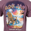 T-shirt featuring an astronaut seated on a chair at a beach watching a colorful sunset. Text reads Ron Jon Surf Shop Cocoa Beach.