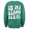 Green sweatshirt with white text reading IN MY BEACH ERA and a flower graphic on the back.