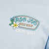 Close-up of a blue shirt featuring a Ron Jon Surf Shop logo with a white flower and the text Cocoa Beach.