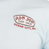 Close-up of a light blue colored shirt featuring a Ron Jon Surf Shop Ocean City, MD logo on the upper left chest.