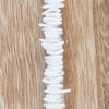 A vertical line of irregularly shaped white stones is arranged on a light wood surface with a natural grain pattern.