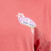 Close-up of a pink T-shirt featuring a small Ron Jon Surf Shop logo with a hibiscus flower design on the left chest area.