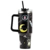 A large black travel mug with a handle, lid, and straw, decorated with cartoon space-themed designs including a crescent moon, planets, stars, and aliens.