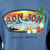 Back of a blue shirt with a colorful Ron Jon Surf Shop logo depicting a beach scene with waves, palm trees, and flowers, labeled Cocoa Beach.