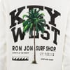 White shirt with Key West text, a large palm tree graphic, and Ron Jon Surf Shop branding, along with coordinates and a wave icon.