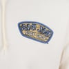 Close-up of a beige hoodie featuring a printed patch with the text Ron Jon Surf Shop, Myrtle Beach in blue and white lettering on a wooden surfboard design.