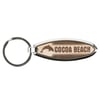 A metal and wood keychain with the text Cocoa Beach and a dolphin image.