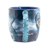 A ceramic mug with a blue handle designed to look like a tentacle, featuring an ocean-themed illustration with more tentacles on the sides.