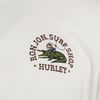 Logo on a white shirt featuring a cartoon cowboy riding an alligator with the text RON JON SURF SHOP HURLEY encircling the design.