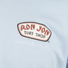 Close-up of a logo on a light blue shirt. The logo reads Ron Jon Surf Shop with Cocoa Beach, Fla. written below.