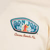 Close-up of a beige shirt with a colorful Ron Jon Surf Shop logo and Cocoa Beach, Fla. text.