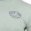 Close-up of a light green T-shirt with a Ron Jon Surfboards, Cocoa Beach, Fla. logo printed on the left chest.