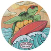 Illustration of a turtle wearing sunglasses surfing on a red surfboard in the ocean with Ron Jon Surf Shop text below.