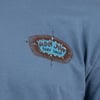 Close-up of a blue shirt featuring a small Ron Jon Surf Shop Cocoa Beach-FL logo with a nautical design on the chest.