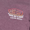 Close-up of a maroon T-shirt with the logo Ron Jon Surf Shop and the text One of a Kind, Cocoa Beach in a colorful design.
