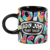 A black ceramic mug featuring a colorful geometric pattern and the Ron Jon Surf Shop logo in white text on the front.