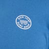 Close-up of a blue shirt featuring a white circular logo that reads Ron Jon Surf Shop Est. 1959 with wave designs.
