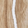 A vertical strand of small, round, white beads is laid out on a light brown wooden surface with visible grain patterns.