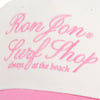Close-up of a beige cap with pink text that says Ron Jon Surf Shop always at the beach embroidered in cursive.