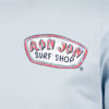 Close-up of a light blue shirt featuring a Ron Jon Surf Shop logo in red and black lettering on the upper left side.