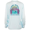 A light blue long-sleeve shirt with a colorful Make Waves Cocoa Beach graphic, featuring ocean waves, flowers, and a sunset on the back.