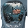 T-shirt design featuring a shark underwater holding a wooden sign that reads Surf Shop, with Cocoa Beach, FL written below.