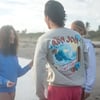 guy standing on the beach talking to a couple of girls, he is wearing the sand blue wave sweatshirt