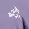 Close-up of a purple shirt featuring a white sea turtle graphic above the text “Ron Jon.”.
