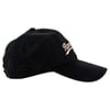 Black baseball cap with white cursive embroidery on the front, viewed from the side.