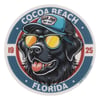 Circular logo featuring a black dog wearing sunglasses and a blue cap labeled Ron Jon Surf Shop, with text reading Cocoa Beach Florida 1925.