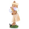 A hula-dancing pig figurine wears a straw skirt, lei, and hat, standing on a decorated base with flowers.