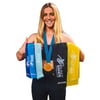 Caroline Marks, wearing a medal, holds five resistance bands labeled heavy, medium, and light. Bands are in three shades of blue, and black and yellow colors.
