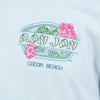 Light blue shirt featuring a Ron Jon Surf Shop Cocoa Beach logo with tropical leaves and two pink hibiscus flowers.