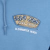 Close-up of a blue garment featuring a Ron Jon Surf Shop Clearwater Beach logo with a wooden surfboard design in the center.