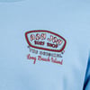 Close-up of a blue shirt with an embroidered "Ron Jon Surf Shop" logo, stating "The Original" and "Long Beach Island.