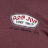 Close-up of a maroon shirt featuring the Ron Jon Surf Shop logo and text, Cocoa Beach, Fla, in white and red font.