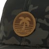 Camouflage hat with a brown patch featuring a palm tree and the text Ron Jon Surf Shop in the center.