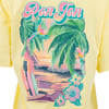A pastel-colored Ron Jon t-shirt features parrots, palm trees, surfboards, a beach hut, and hibiscus flowers with a sunset background.