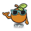 Cartoon orange with teal sunglasses, a green leaf, and brown stem, making a shaka hand gesture. Text below reads Ron Jon Surf Shop Little Box Guy.