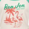 A t-shirt with a Ron Jon Surf Shop logo above an illustration of two flamingos, a palm tree, and birds, all in red and green.