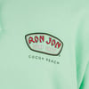 A light green shirt featuring the Ron Jon Surf Shop, Cocoa Beach logo.